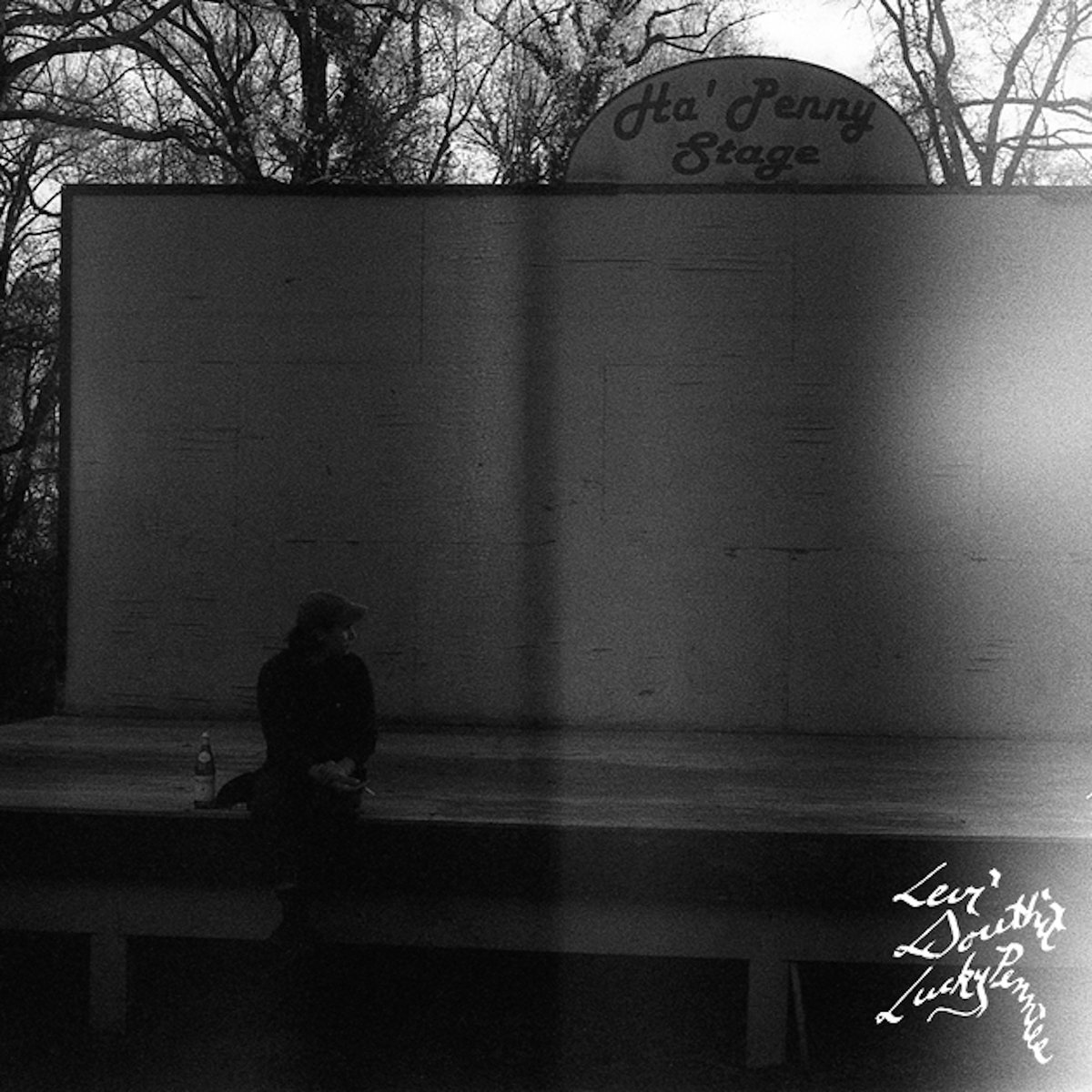 levi douthit lucky pennies album art - black and white photo of a man sitting on an outdoor stage