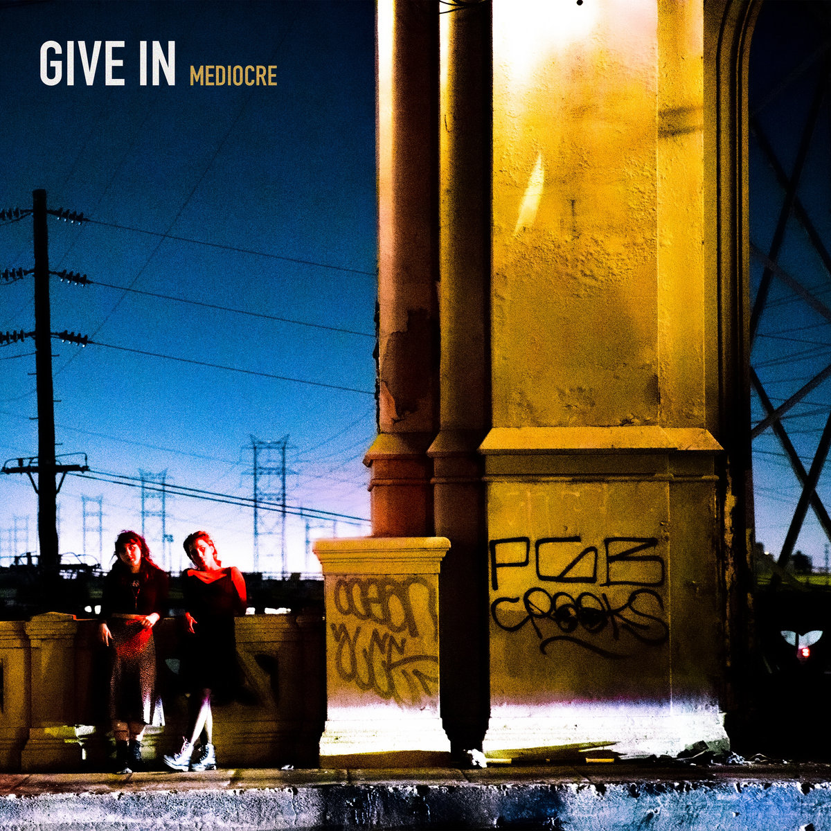 Mediocre Give In single art - two people standing next to a large stone pillar at night