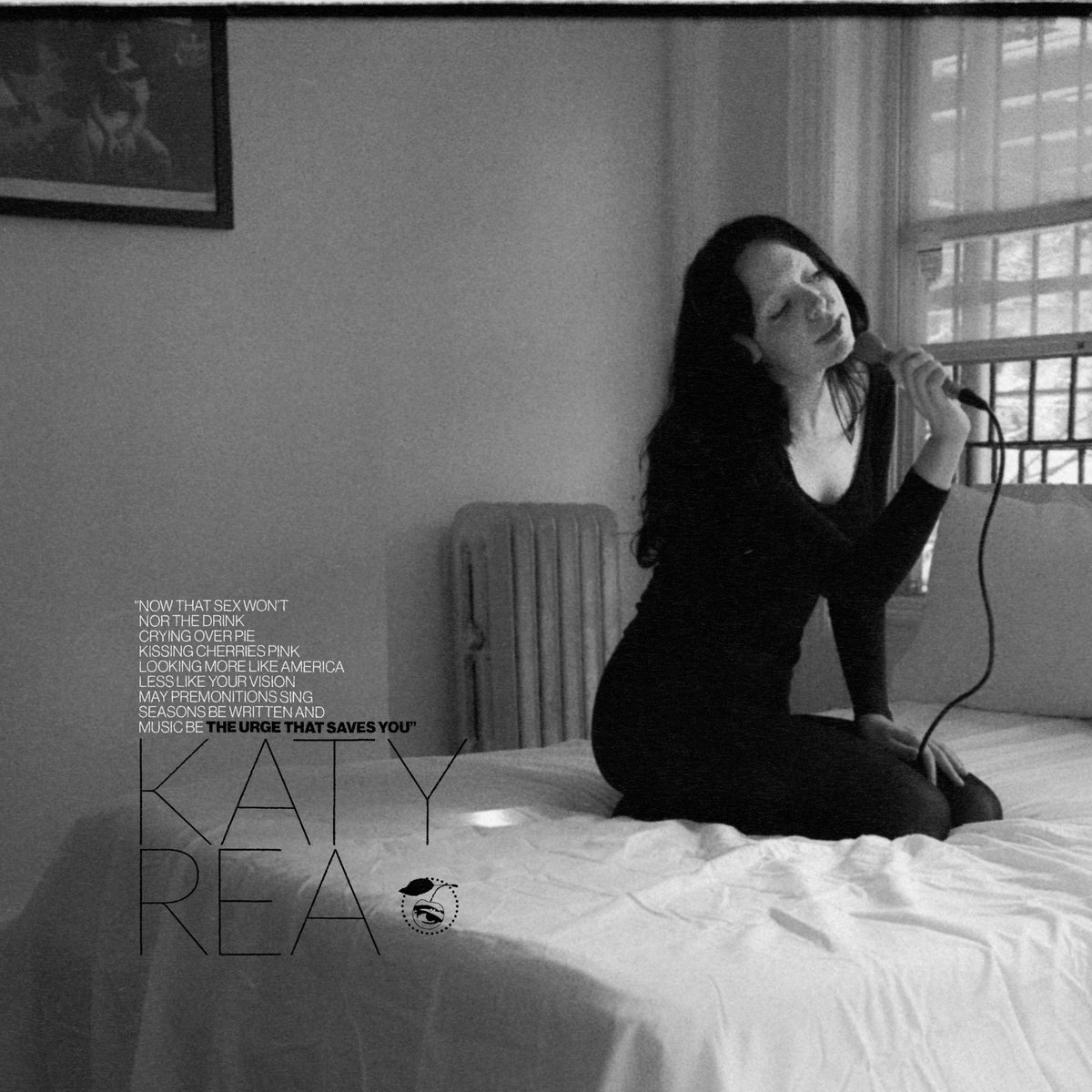Katy Rea The Urge That Saves You album art - black and white photo of Katy Rea kneeling on a bed and singing into a microphone