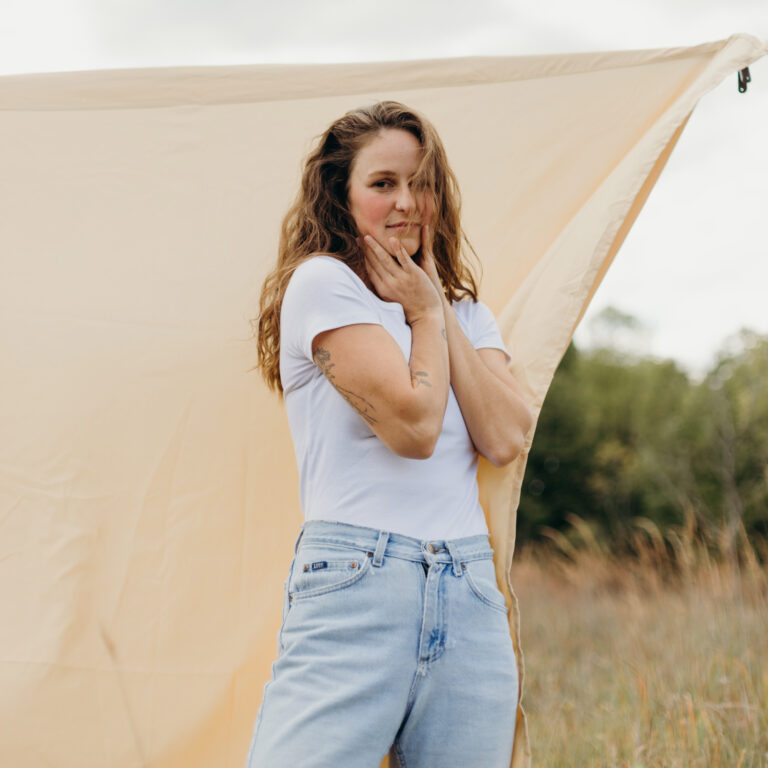 a photo portrait of canadian artist Rose Brokenshire. She is wearing a white t-shirt and pale blue jeans