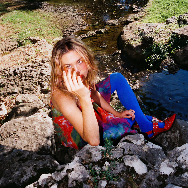 Melanie MacLaren Bloodlust EP cover - photo of MacLaren sitting next to a stream