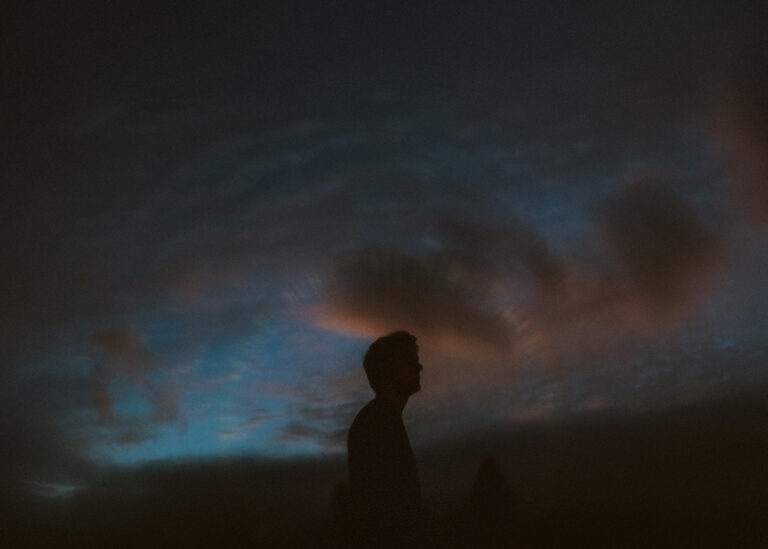 photograph of David Allred in silhouette against an evening sky